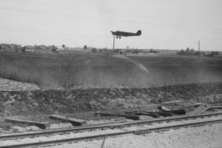 Landing German plane at the airport in Małe Raczki. In the background the village buildings. 1941. Lądujący niemiecki samolot na lotnisku w Małych Raczkach. W tle zabudowania wsi. 1941.